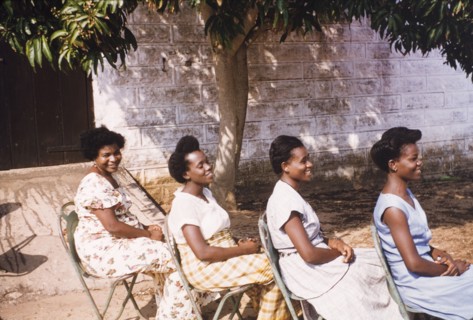 Hairstyles of four Ghanaian women. Four female Assistant Education Officers sit in a row in