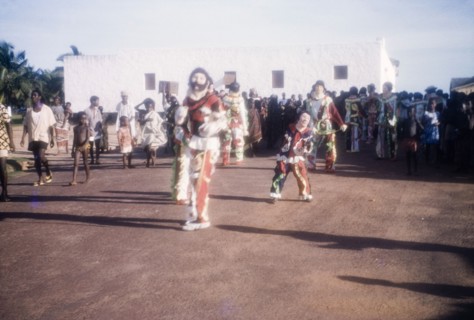 Performing masqueraders. Costumed masqueraders perform at an outdoor ceremony to celebrate Ghana
