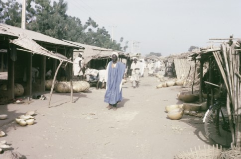 Marketplace in Kano. Stalls with thatched canopies shelter goods from the sun in a busy marketplace
