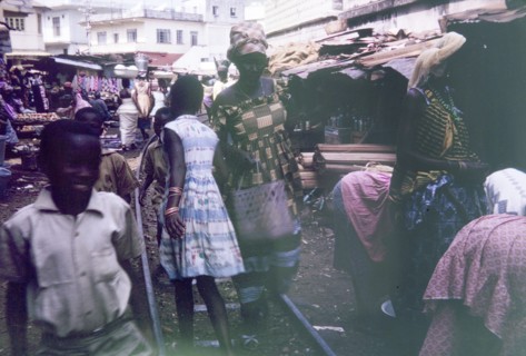 Old railway track running through Freetown market. Shoppers walk along a disused railway track