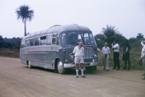 A broken-down bus. Inconvenienced European passengers stand on a roadside beside a broken-down bus,