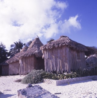 Beach huts at San Pedro, Belize. Four square, bamboo beach huts with thatched roofs stand in a row