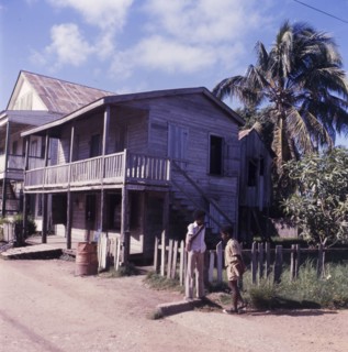 Wooden house in Belize. Two boys chat on a street corner outside a wooden, two-storey house in