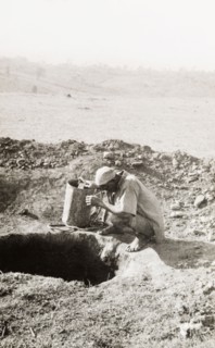Exploratory mine shaft at the Kakamega goldfields. A labourer squats at the opening to a mine shaft
