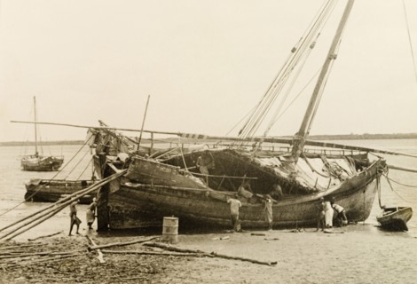 Repairing a dhow at Lamu, Kenya. Men repair a dhow, which is dry-docked on a beach at Lamu. Lamu,