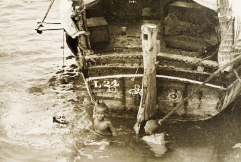 Children playing in Old Mombasa harbour. Three children play at the stern of a dhow in the shallow