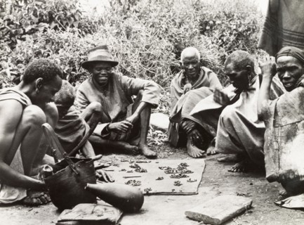 Telling fortunes by beans'. A group of Kikuyu men gather around to read their fortunes by