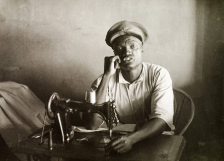 A Swahili tailor. A Swahili tailor sits behind a sewing machine at his work desk in Mombasa.