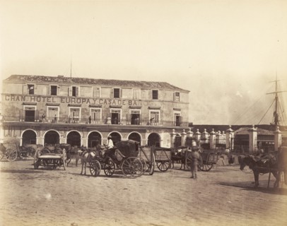 Gran Hotel Europa, Cuba. Horse-drawn wagons and carts pull up on a cobbled road outside the Gran