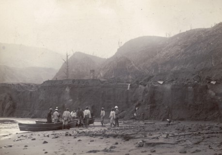 Wallibu dry river. Men stand beside canoes on the muddy bed of Wallibu River. The river was forced