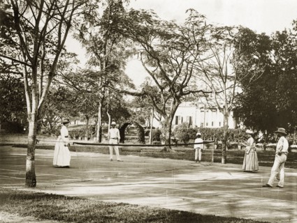 A colonial doubles match. Two British couples play doubles on a tennis court in the grounds of a