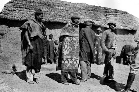 African men outside a hut. African men, possibly members of a Bantu-speaking tribe, mill about in