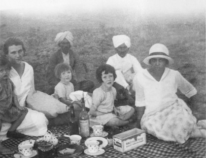 A family picnic in India. A British family enjoys a picnic outdoors, accompanied by three Indian