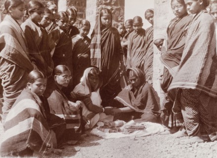 Women trying on bracelets. A group of Indian women in saris gather around a street vendor who sells
