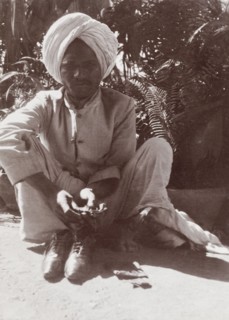 Indian man in Karachi. An Indian man squats on a street in Karachi, barefoot with his shoes