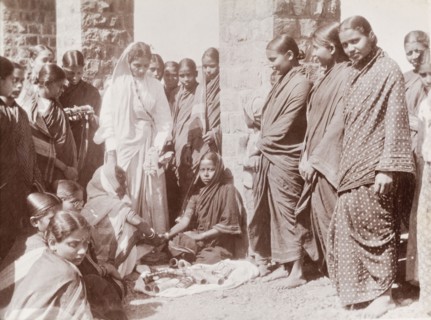 Women trying on bracelets. A group of Indian women in saris gather around a street vendor who sells