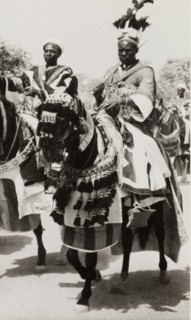 Nigerian chief riding a caparisoned horse. A Nigerian chief wearing an elaborate feathered