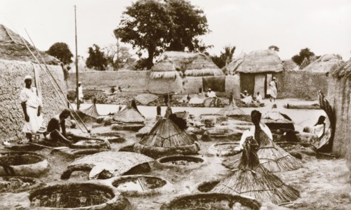 Dye wells in Zaria. Textile workers sit outdoors, dipping lengths of fabric into wells of dye,
