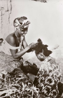 Hairdressing in Jos'. A Nigerian hairdresser smiles as she styles a customer's hair. Jos, Nigeria,