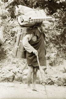 Burdened with luggage. An Indian man carries cumbersome bundles of luggage on his back as he walks