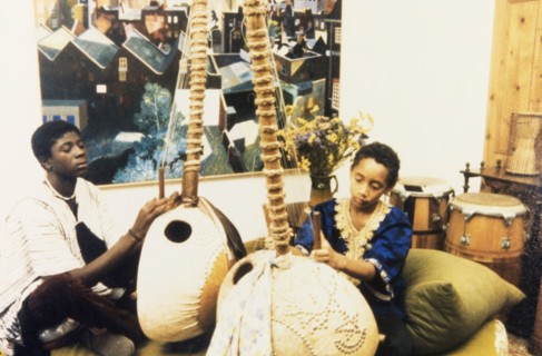 Musicians at the West African Music Village. Two young musicians adjust the strings of their lutes