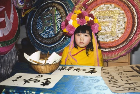 Chinese girl in a flower headdress. A young Chinese girl wears a headdress made of flowers as she