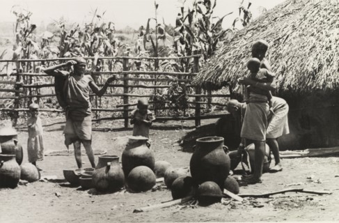 A Kikuyu family pottery'. Three Kikuyu women look after several small children as they make clay