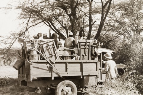 Jeep made ready for safari. African porters sit amongst a jumble of folding tables and chairs in