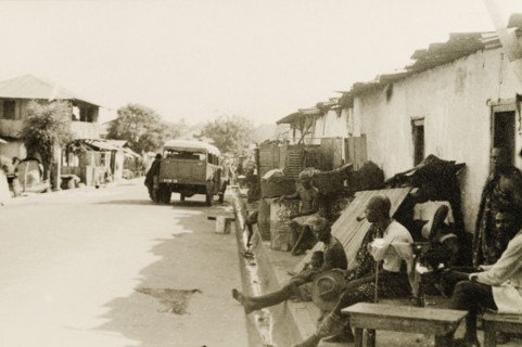 A side street in Accra. A concrete drainage ditch runs along a side street in Accra, where a group