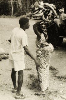 Gold Coast courtesy'. A man helps his wife to arrange her load as she attempts to balance a bowl of