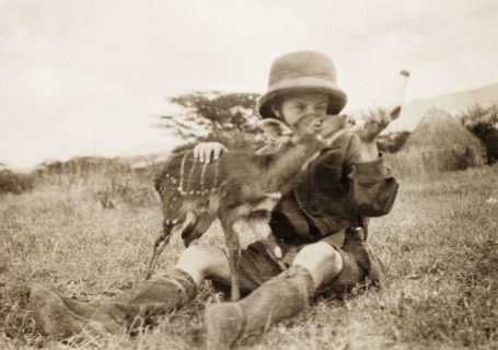 Elspeth Grant feeds an antelope calf. Elspeth Grant (later Huxley) sits on the grass feeding milk