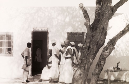 Queueing to see the District Officer. A group of Somali men queue outside an office building for an