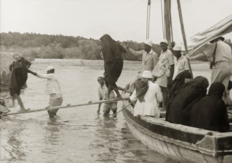 Disembarking at Mombasa Island. Arabic men assist a group of veiled Muslim women to cross a
