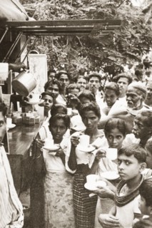 Drinking tea from a mobile kiosk. A group of people crowd around the hatch of a mobile kiosk, where