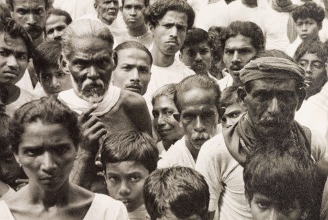 A crowd of Ceylonian people. A tightly packed crowd of people gaze solemnly into the camera. Ceylon