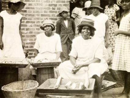 Fish stall in St Lucia. A female trader sits smoking a pipe at her street stall, where she sells
