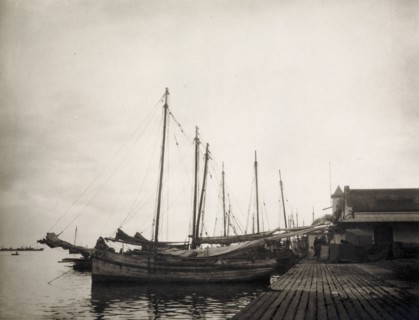 A harbour at Port of Spain. A row of sailing boats is moored to a landing stage at Port of Spain