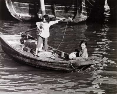 Chinese girls steer a sampan. Two girls travel aboard a scull-propelled sampan in Aberdeen Harbour,