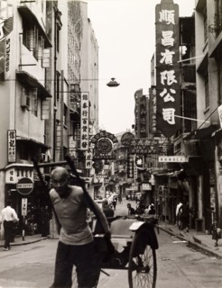 Rickshaw driver in Hong Kong. A rickshaw driver pulls his empty carriage along a commerical street