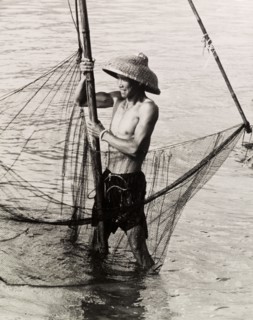 Fishing in shallow waters. A fisherman trawls his net in the shallow waters of a Hong Kong bay.