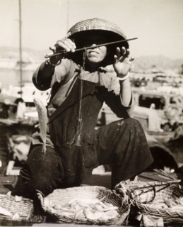 Weighing the day's catch. A fisherman weighs the fish from his day's catch at a harbour in Hong