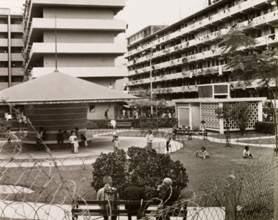 Resettlement blocks in Kowloon. Children play in a fenced park surrounded by multi-storey