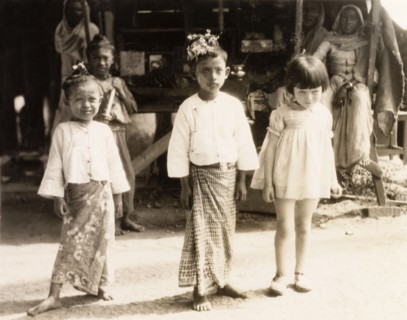 Children in Rangoon. A young British girl poses with two Burmese children wearing traditional