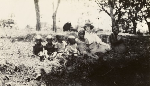 European woman with Chaga children. A European woman sits on a grassy bank with a Chaga woman and
