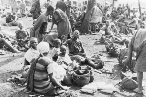 A homegrown vegetable market . Women and children sit together in groups at an outdoor market,