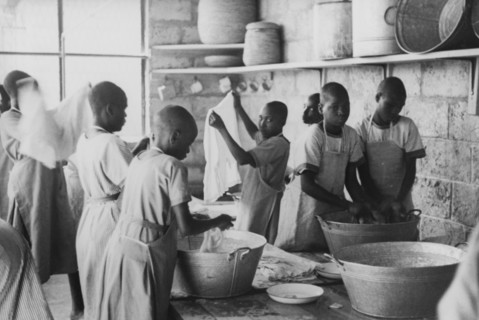 Laundry at a mission school. Kikuyu boys dressed in Western-style uniforms and aprons wash clothes