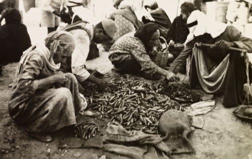 Okra seller, Palestine. Shoppers select okra from a stall at a Palestinian market, which the trader