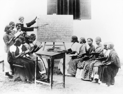 English lesson at a mission school, India. An Indian teacher points to a blackboard as he gives an