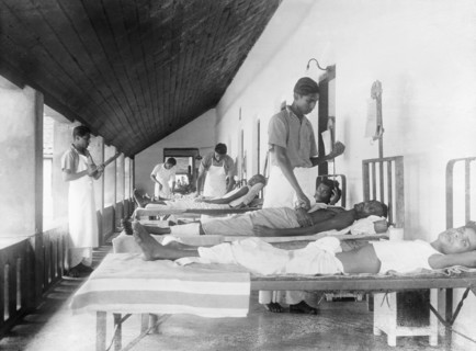 Male ward of a mission hospital, India. Indian medical officers tend to bedridden patients on the
