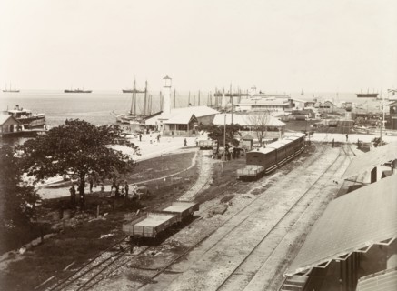 Port of Spain wharf. Empty freight cars and passenger carriages sit on sidings at Port of Spain